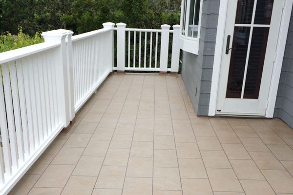 White railing on a deck with a tile-look coating
