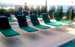 green lounge chairs on a beige pool deck coated with Orange County cool decking waterproof coatings