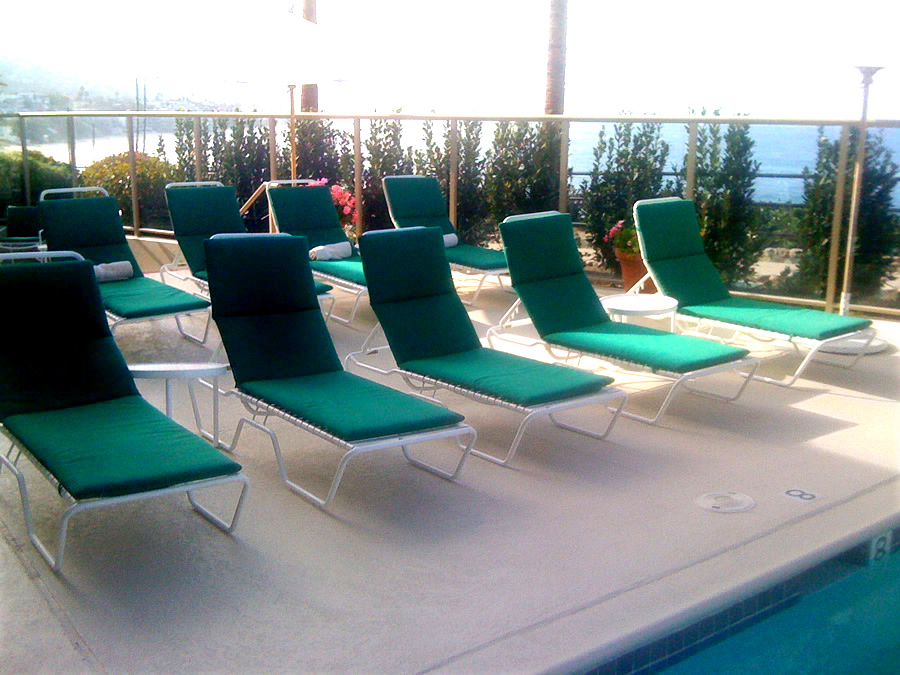 green lounge chairs on a beige pool deck coated with Orange County deck waterproofingcoatings