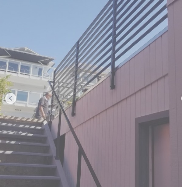 custom deck railings and stairway railings in brown on a pink stucco building