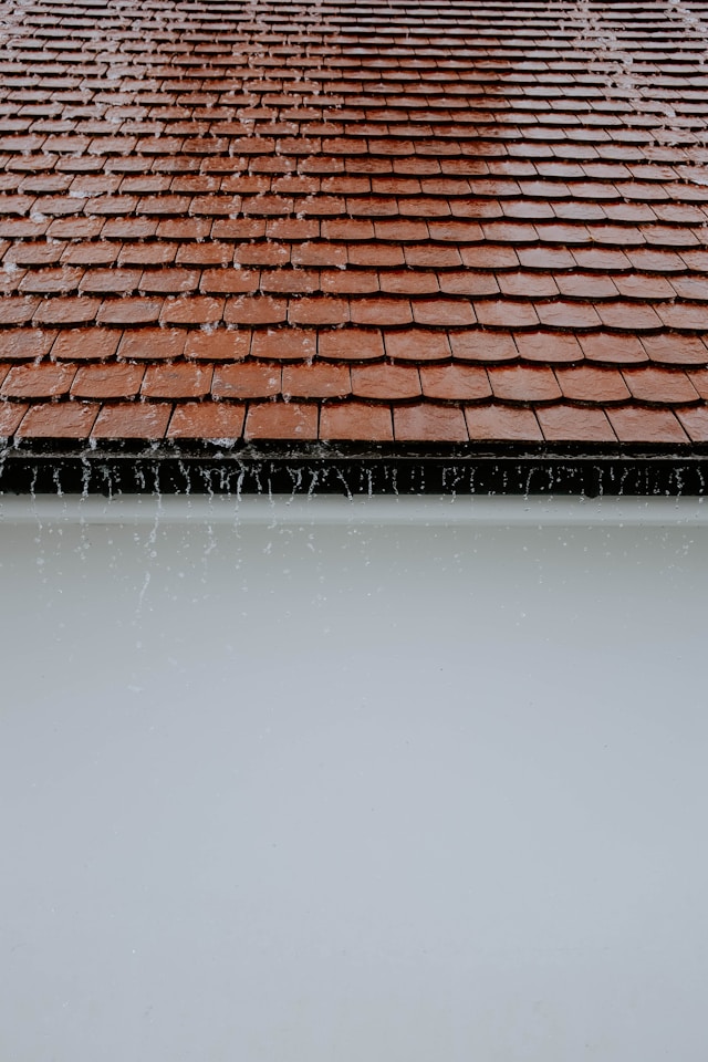 water running from red tile roof that needs roof repairs