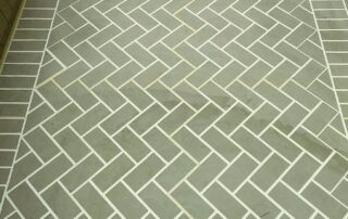 After concrete resurfacing with a walkway coating that creates a green herringbone brick pattern