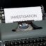 typewriter with paper and word investigation